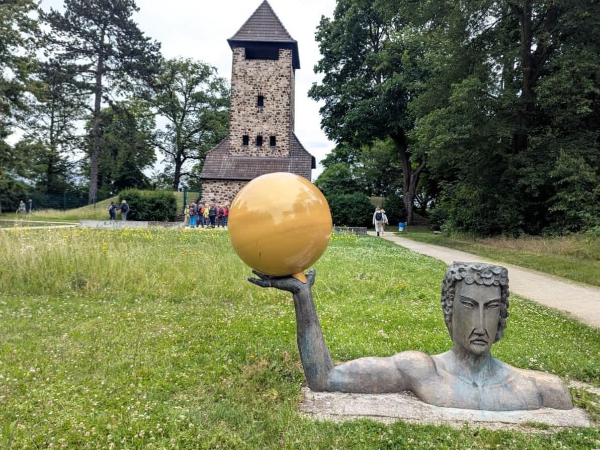 moderne Planeten-Skulpturmit dem historischen Sternwarten-Turm im Hintergrund.