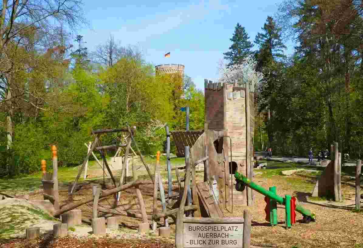 Blick vom Abenteuerspielplatz in Auerbach auf die im Hintergrund thronende Burgruine Schloss Auerbach an einem sonnigen Frühlingstag Blick vom Abenteuerspielplatz in Auerbach auf die im Hintergrund thronende Burgruine Schloss Auerbach an einem sonnigen Frühlingstag