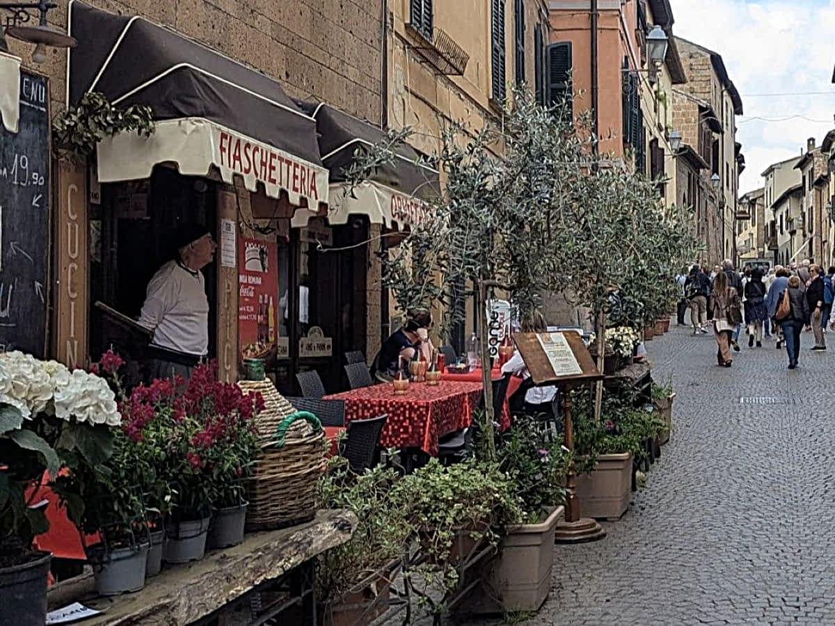Belebte Gasse in Orvieto mit Restaurants und Menschen.
