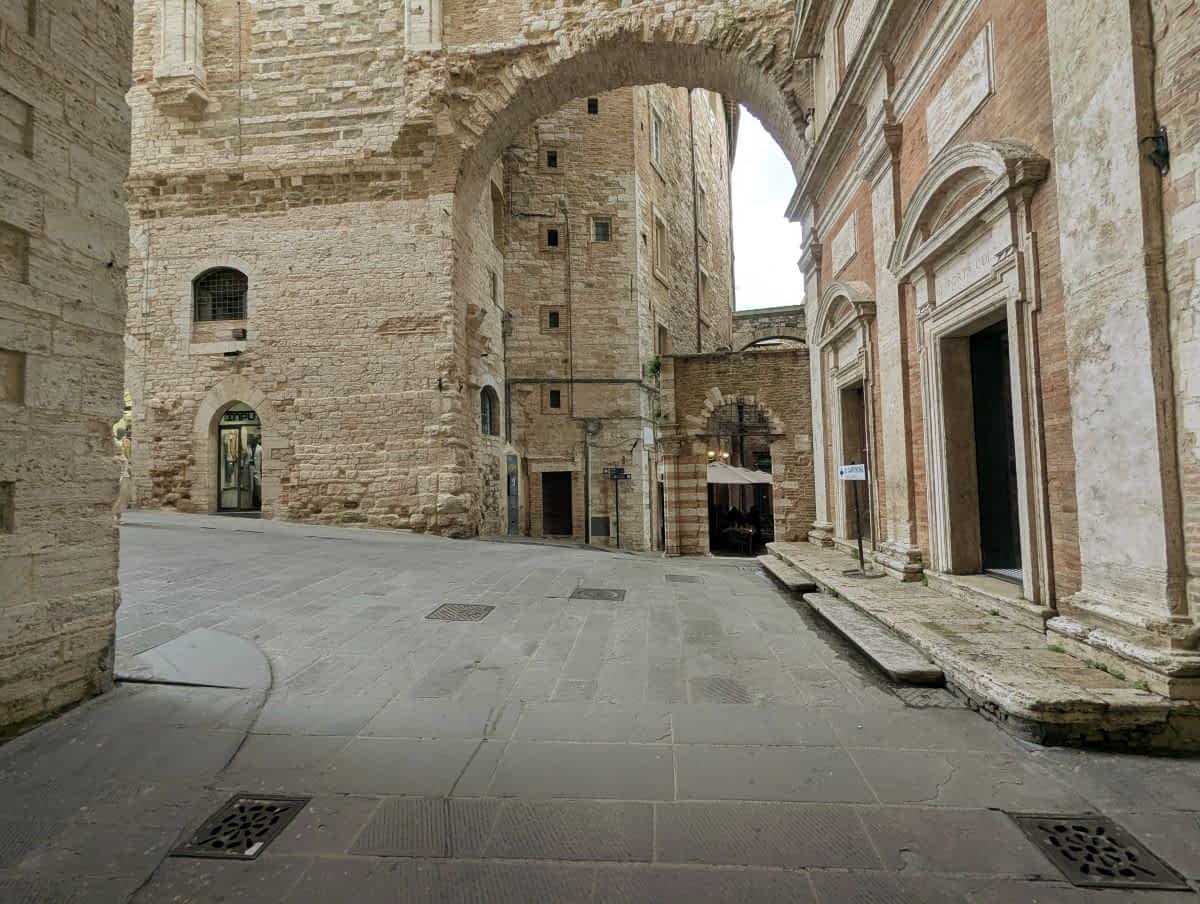 Antike Gasse in Perugias Altstadt mit einem großen Steinbogen und historischen Gebäuden.