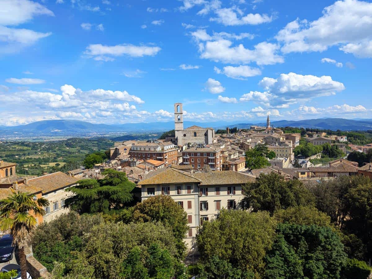 Panoramablick auf Perugia, Italien, mit historischen Gebäuden und grünen Hügeln.