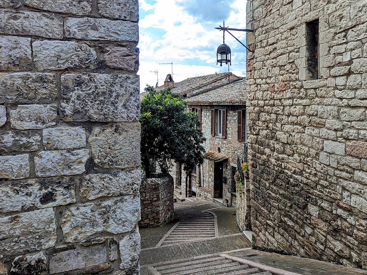 Mittelalterliche Gasse in Assisi, umrahmt von historischen Steinmauern