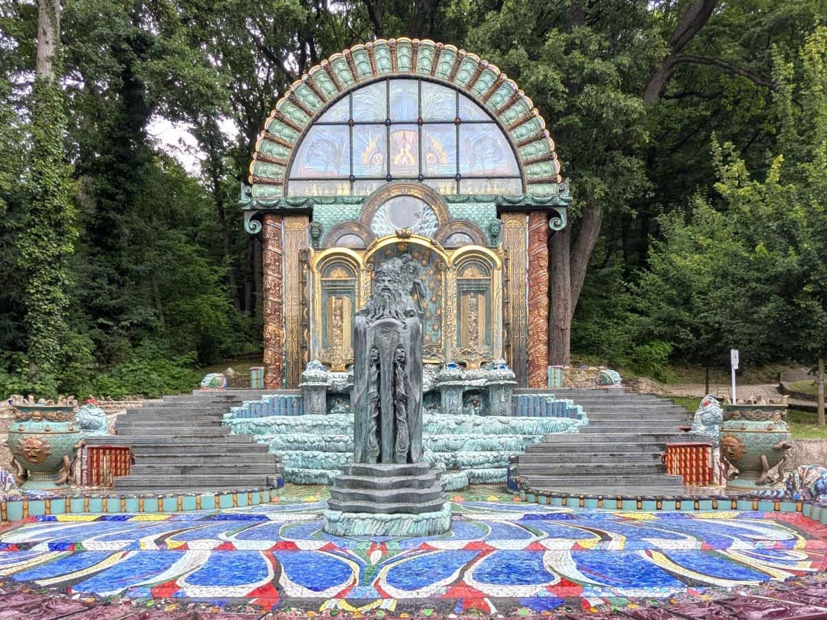 prunkvoller Jugendstil-Gartenbrunnen mit buntem Mosaikboden, einer zentralen Bronzestatue und einem kunstvollen, halbkreisförmigen Buntglasaufbau, umgeben von Bäumen otto wagner villa wien
